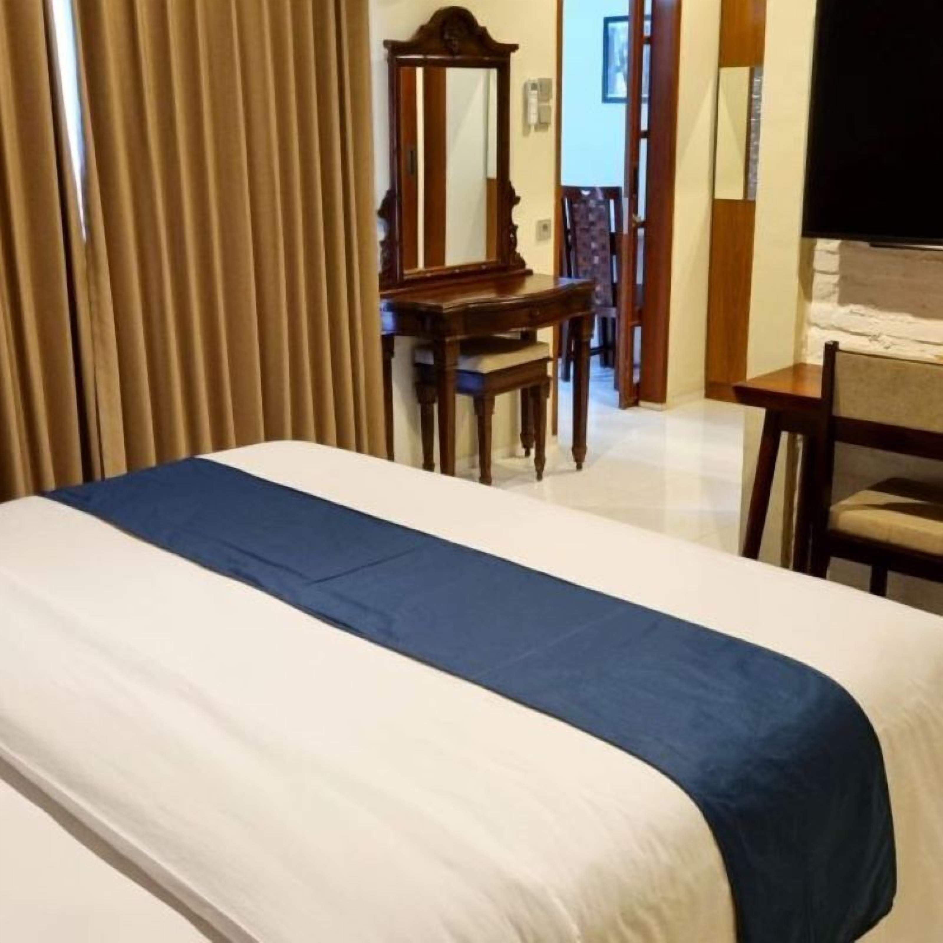 A hotel room with a bed, a desk, and a chair.