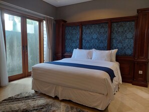 A bedroom with a large bed, wooden headboard, and a view through a sliding glass door.