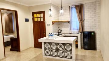 A compact kitchen with a central island, a refrigerator, and a window with curtains.