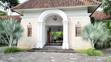A building with a white facade, a tiled roof, and a central entrance with an archway.