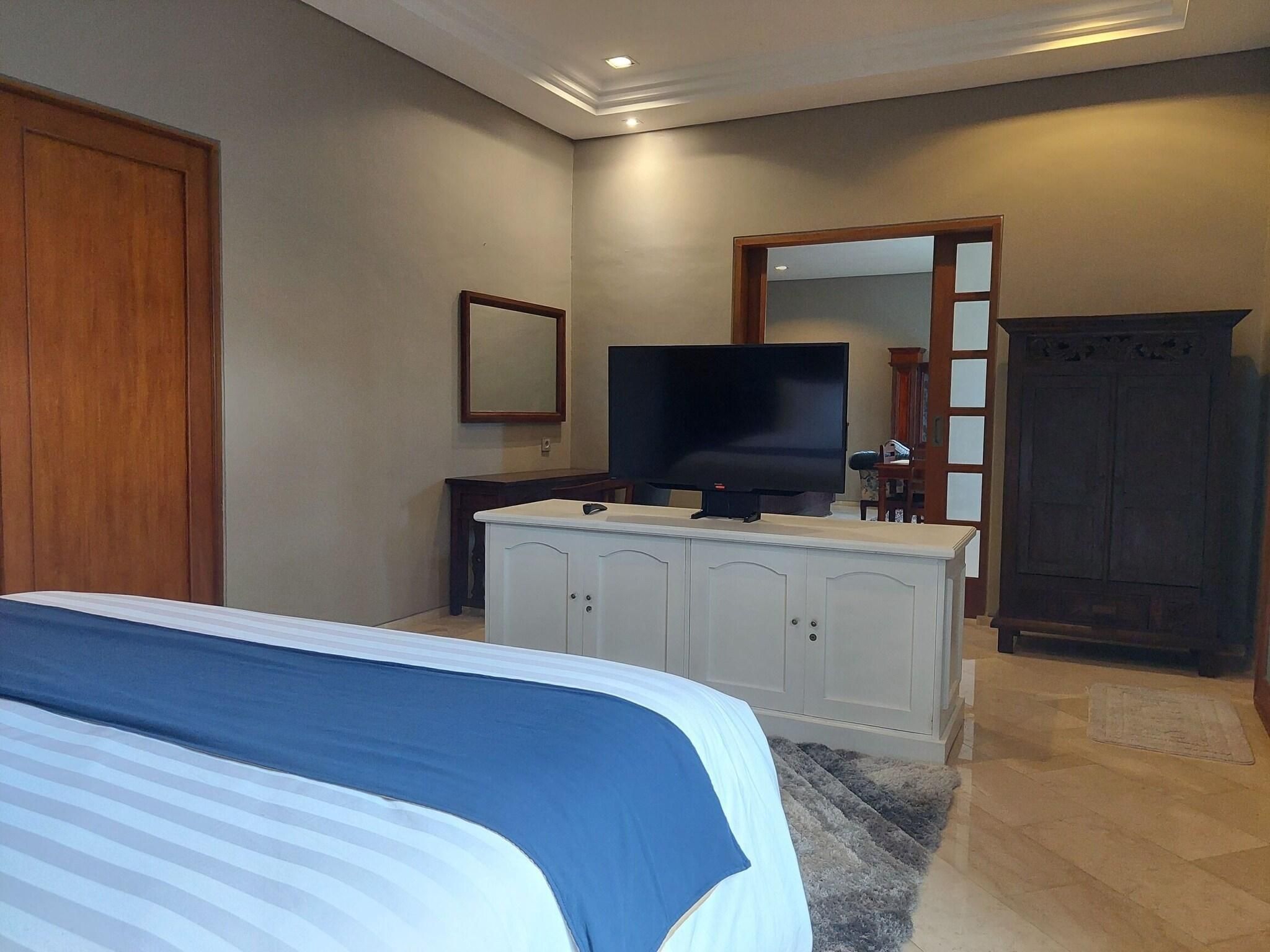 A bedroom with a bed, a TV, a dresser, and a wardrobe.