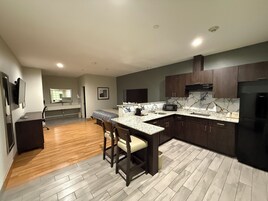 Una cocina moderna con alacenas de madera oscura, encimera de mármol y refrigerador negro.