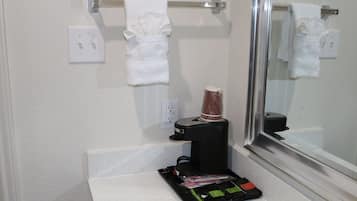 A bathroom with a towel rack, a coffee machine, and a mirror.