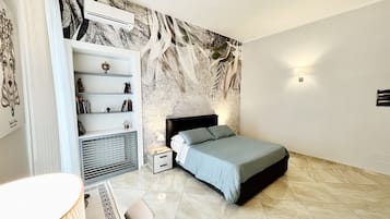 A bedroom with a bed, a nightstand, a shelf unit, and a wall mural.