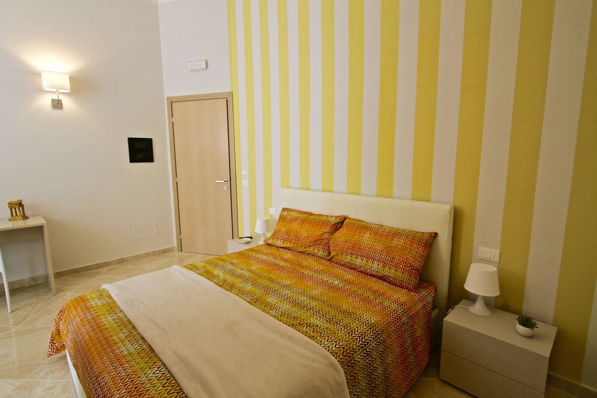 Un dormitorio ordenado con cama, mesita de noche y lámpara.