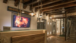 Un espace d’accueil doté d’un comptoir en bois, de luminaires suspendus et d’un grand tableau encadré au mur.