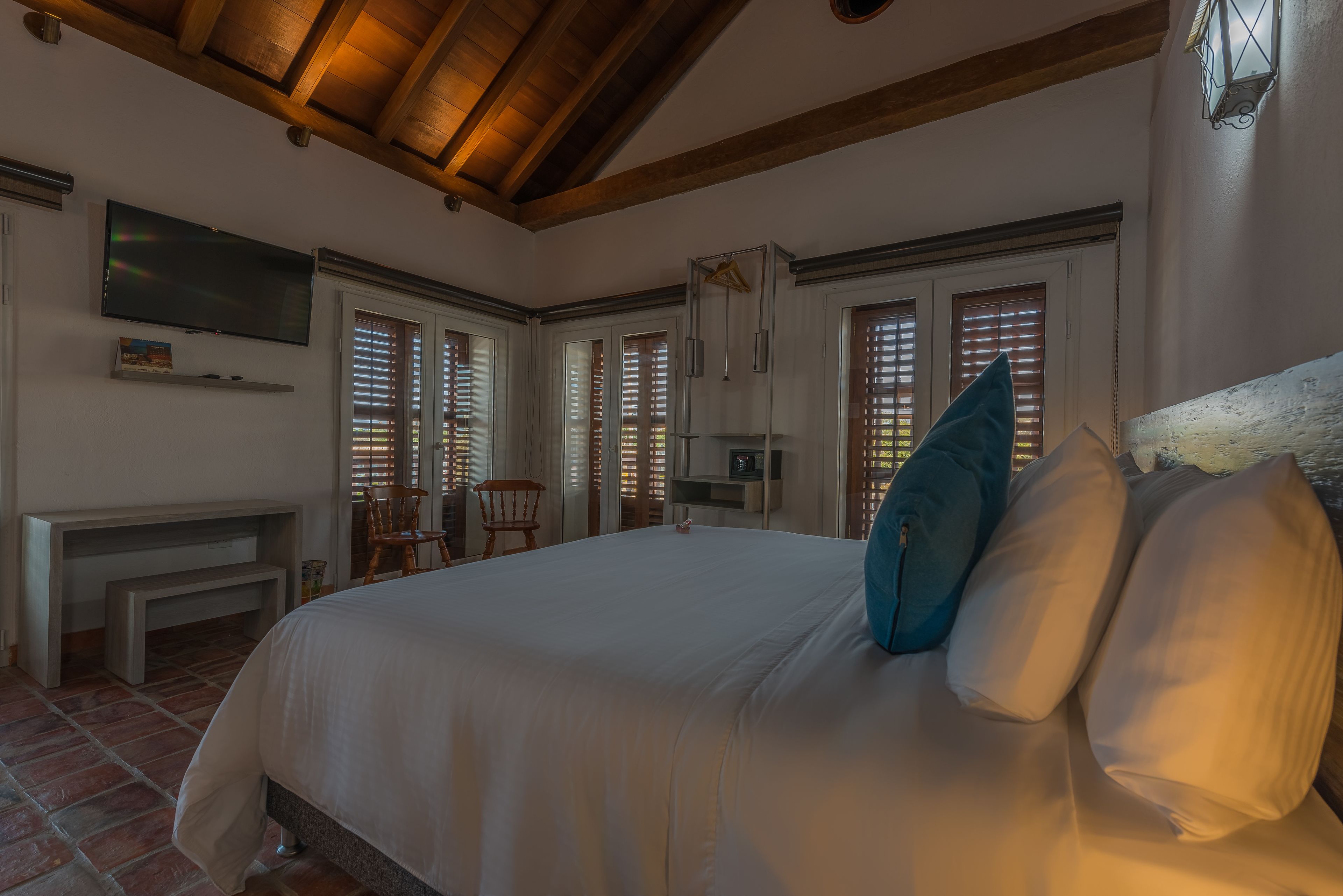 A bedroom with a large bed, a television, a desk, and a chair.