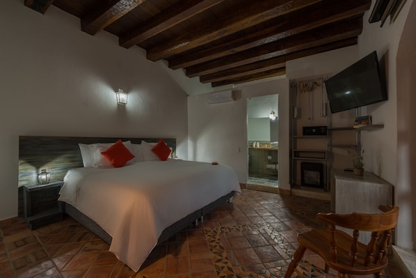Un dormitorio con cama, televisión, sillón y chimenea.