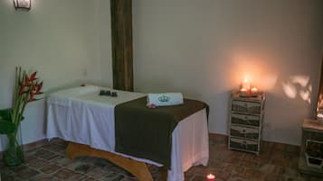 Relax in this serene spa room with a single bed, a wooden bench, and a vase with flowers.