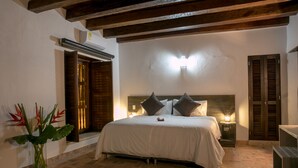 Une chambre à coucher comprenant un lit, des tables de chevet, une commode, une lampe fixée au mur et un plafond en bois.