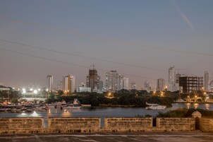 Une vue sur la ville, avec ses bâtiments de grande hauteur, son port de plaisance rempli de bateaux et un mur de pierre au premier plan.