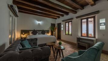 Un dormitorio con cama, sofá, una mesita y ventana con vistas.