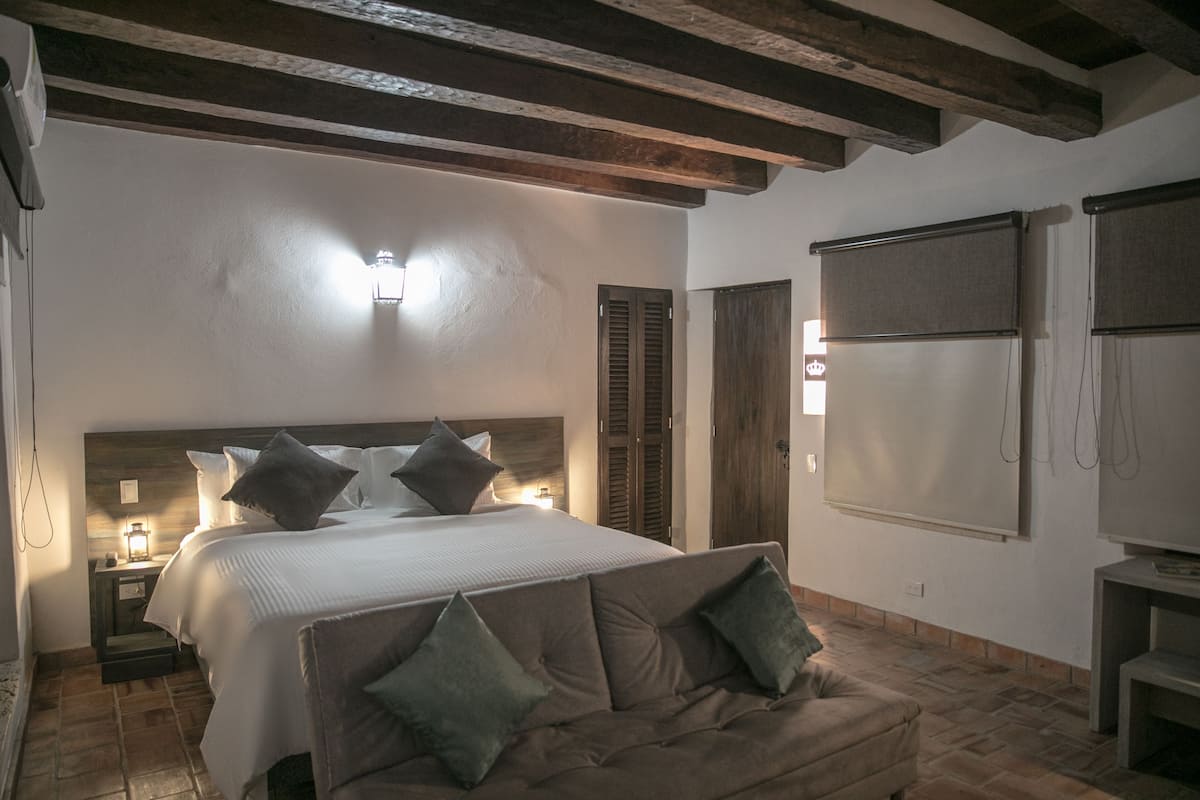 Une chambre à coucher avec un grand lit, une tête de lit en bois, une table de chevet avec une lampe et un canapé.