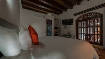 Un dormitorio con cama, almohadas, televisor, ventana con vistas y techo de madera.