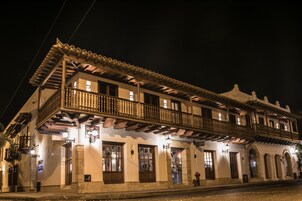 Un edificio histórico con balcón y múltiples ventanas, que presenta un estilo arquitectónico tradicional.