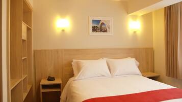 Habitación de hotel con cama, mesita de noche, teléfono y un cuadro en la pared.