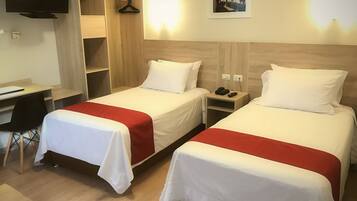 Habitación de hotel con dos camas, un escritorio, una silla, un televisor y un cuadro en la pared.