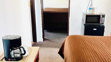 A hotel room with a bed, a coffee maker, a microwave, and a television.