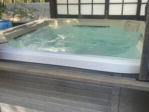 A hot tub with a wooden deck surrounding it.