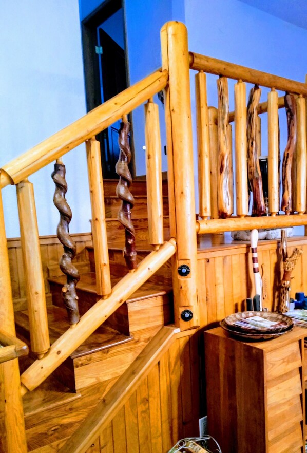 Eine Holztreppe mit einer markanten, gedrehten Gestaltung der Geländer und einer Holzwand im Hintergrund mit einer Tür.