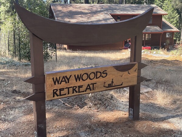 Ein Holzschild mit dem Schriftzug 'WAY WOODS RETREAT' und einer Illustration eines Kanus.