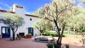 Un patio con un edificio blanco, puertas azules y un área de patio con azulejos.