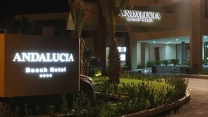 Andalucia Beach Hotels facade med et skilt og en velholdt have.