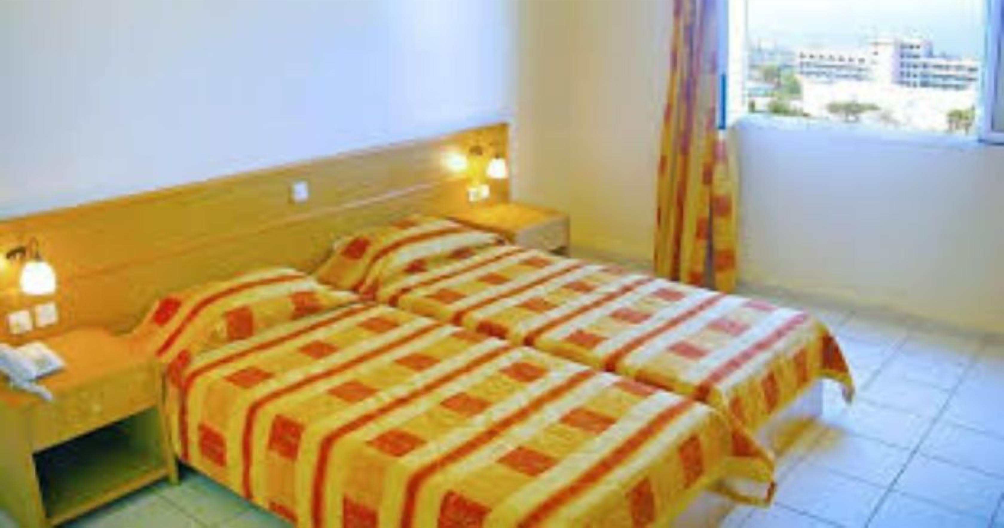A hotel room with two beds, a nightstand, and a window with curtains.