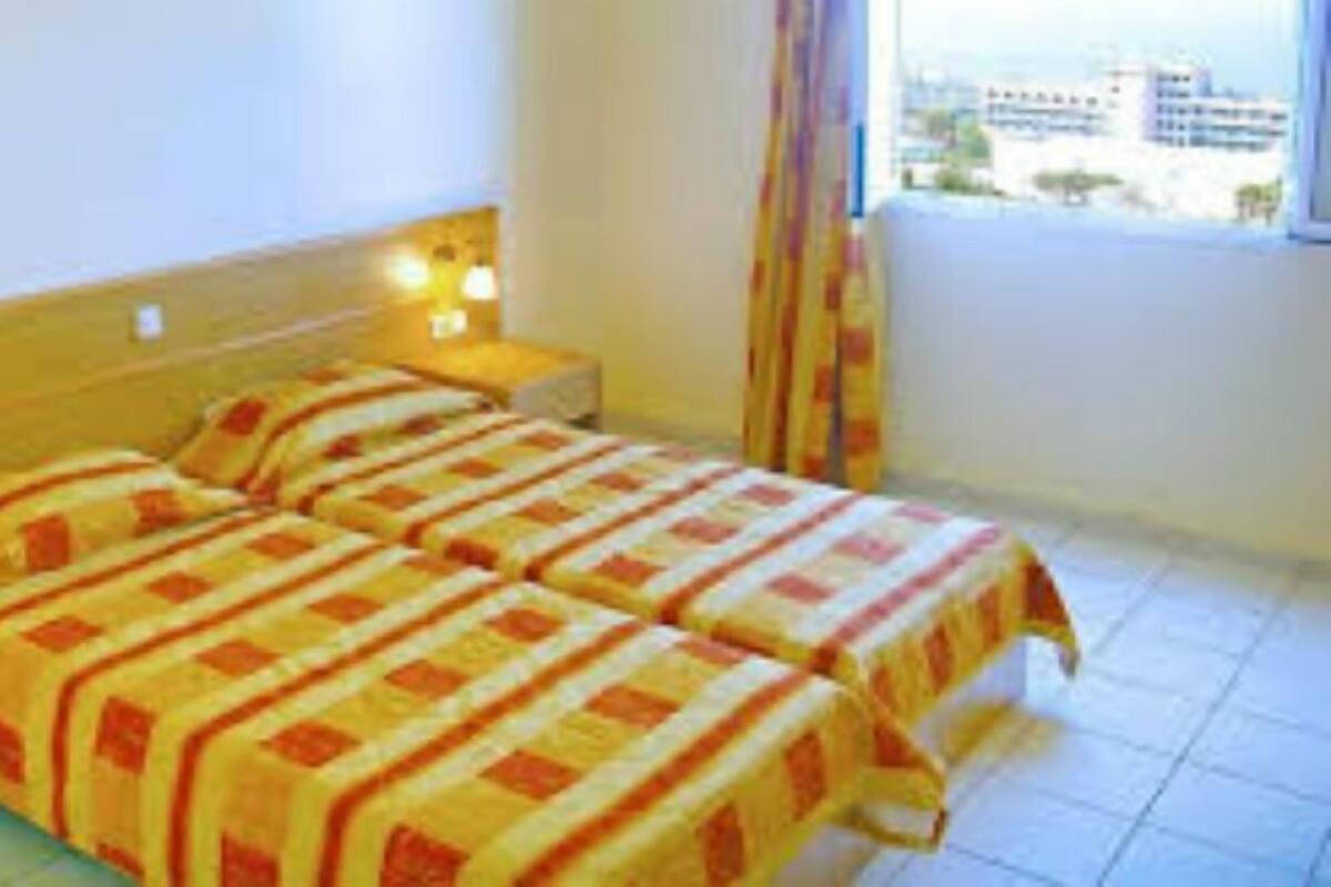 A hotel room with two beds, a nightstand, and a window with curtains.