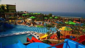 A water park with multiple slides and pools, surrounded by umbrellas and lounge areas. - Aqua Sun Village (Hersonissos)
