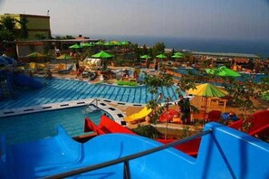 A water park with multiple slides and pools, surrounded by umbrellas and lounge areas. - Aqua Sun Village (Hersonissos)