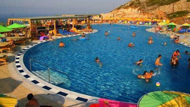 A large outdoor swimming pool with multiple lanes, surrounded by beach chairs and umbrellas.