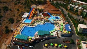 An aerial view of a resort with multiple swimming pools, a water slide, and sun loungers. - Aqua Sun Village (Hersonissos)
