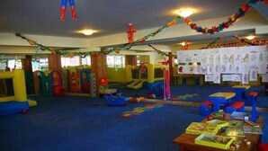 A playroom with colorful play structures, a carpeted floor, and a table with books and toys.