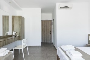 A modern hotel room with a wooden vanity, a white chair, a bed with neatly folded towels, and a large mirror. - Kahlua Boutique Hotel (Hersonissos)
