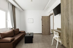 A modern living room with a brown sofa, a black coffee table, and a TV mounted on the wall.