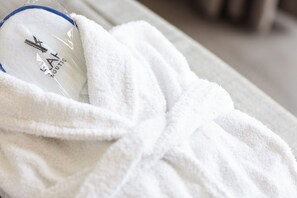 A white bathrobe on a bed with a visible logo and text.