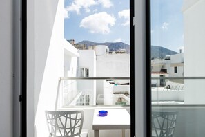 A balcony with a table and chairs, overlooking a cityscape with buildings and a mountain. - Kahlua Boutique Hotel (Hersonissos)
