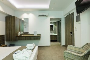 Une chambre d’hôtel moderne comprenant un lit, un coin salon, une salle de bain avec un miroir et un téléviseur.