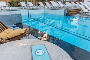 A clear blue infinity pool with lounge chairs and a wooden deck. - Kahlua Boutique Hotel (Hersonissos)