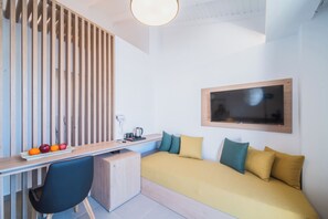 A modern room with a desk, a chair, a bed with pillows, a mounted TV, and a fruit bowl. - Kahlua Boutique Hotel (Hersonissos)