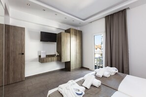 A hotel room with a bed, a TV mounted on the wall, a wooden wardrobe, and a window with curtains. - Kahlua Boutique Hotel (Hersonissos)