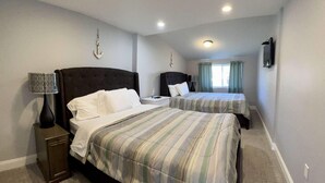 Una camera d'albergo con due letti, un comodino con una lampada e un piccolo tavolo.