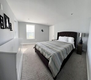 A bedroom with a large bed, a bedside table, a lamp, and a window.