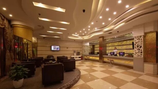 A hotel lobby with a checkered floor, seating area, reception desk, and a TV screen. - Yiwu Chuzhou Hotel (Jinhua)