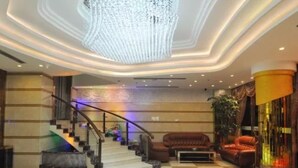 A lobby with a checkered floor, a staircase, a chandelier, and a seating area with a sofa and armchair. - Yiwu Chuzhou Hotel (Jinhua)