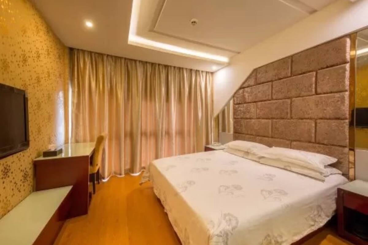 A hotel room with a large bed, a desk, and a TV.