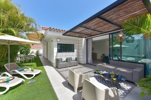 Un espacio exterior moderno con patio, zona de estar y una sección cubierta.