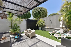 A modern outdoor patio with seating, a small garden, and a black gate. - Cosy Bungalow for 6 in Playa del Ingles GD04 (San Bartolomé de Tirajana)