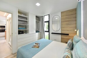 Un dormitorio con cama, armario, espejo y vistas a un jardín.